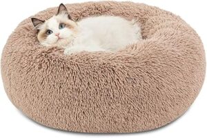 A brown, round cat bed made out of faux fur with a ragdoll cat laying in it